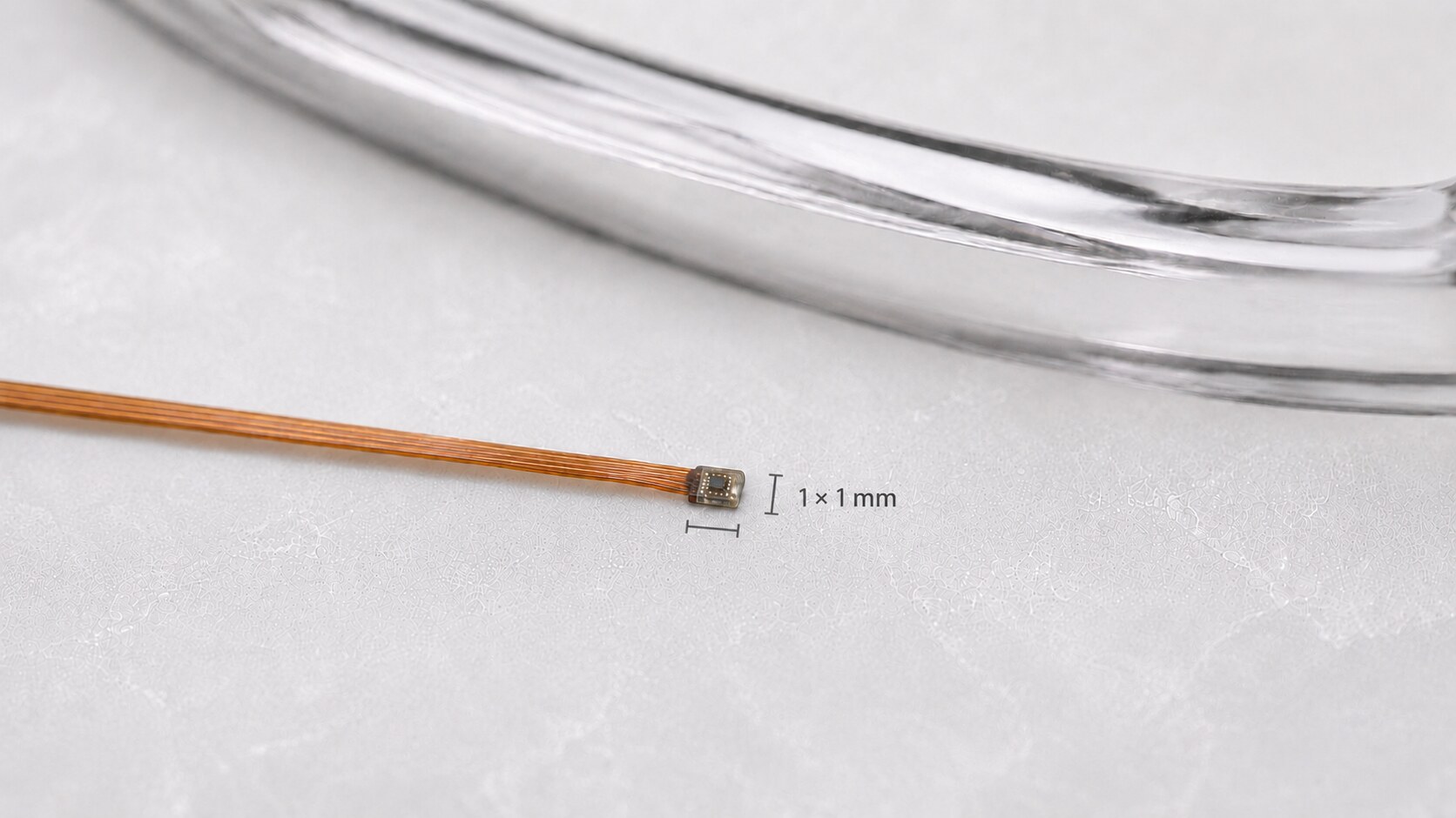 The Motia sensor module on its flex cable beside a clear eyewear frame, annotated to show the sensing element measuring 1 by 1 millimetre